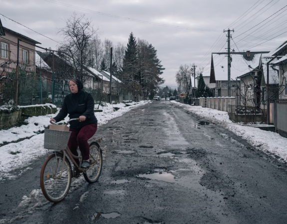 Велосипедистка крутит педали по жилой улице в украинском городе Вышково, недалеко от границы с Румынией.